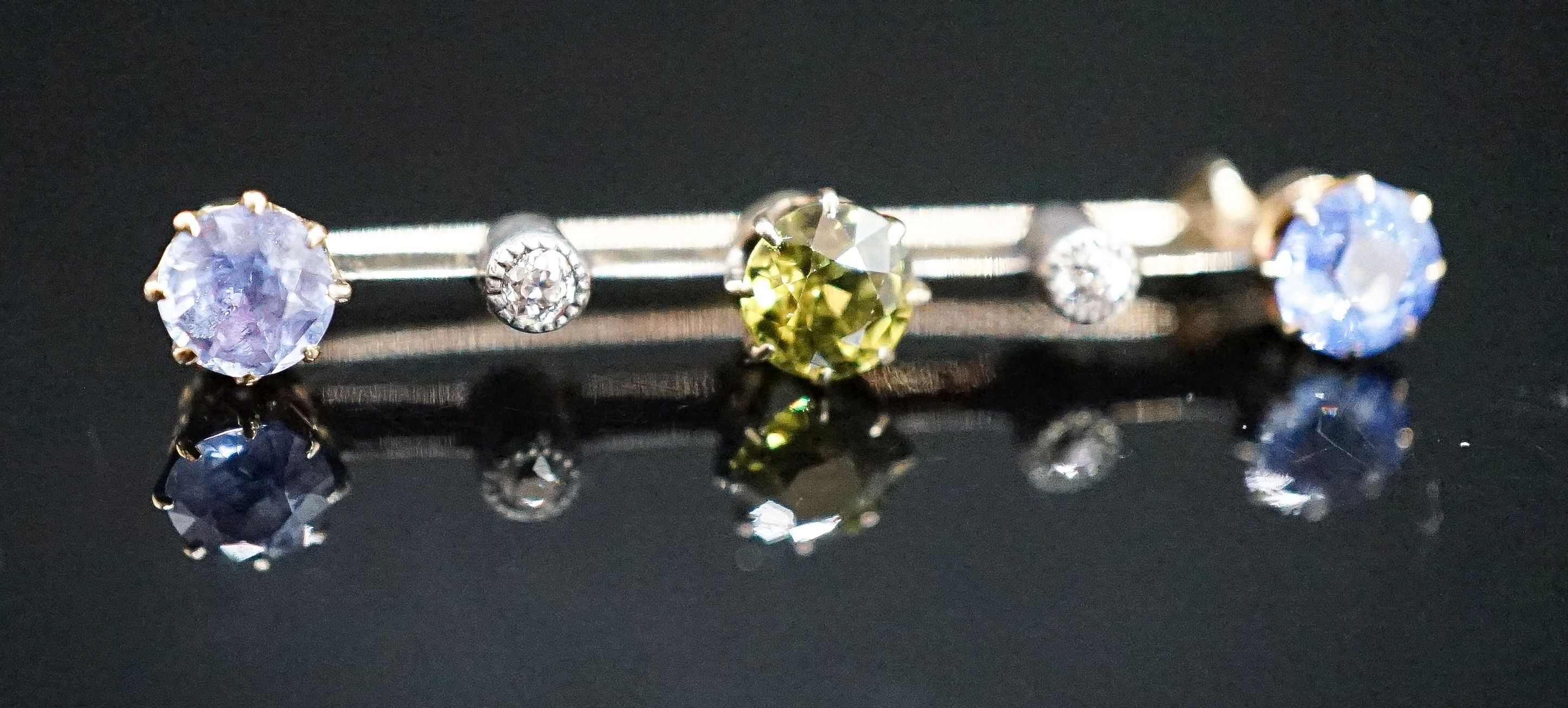 A yellow metal, single stone garnet?, two stone Ceylon sapphire and two stone diamond chip set bar brooch, 37mm, gross weight 2.8 grams.